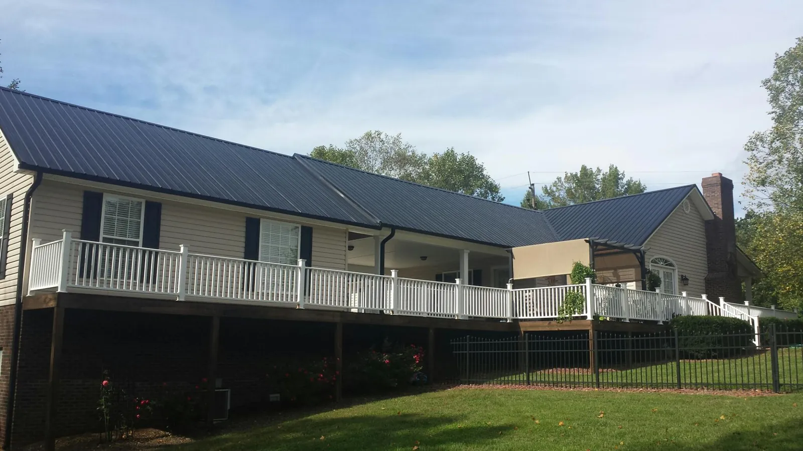 Black metal roof above a long white railed deck on a hillside home in Seabrook